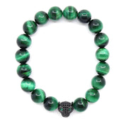 Overhead view of a green tiger's eye bracelet with round banded beads and a black jaguar head set with clear stones and green eyes.