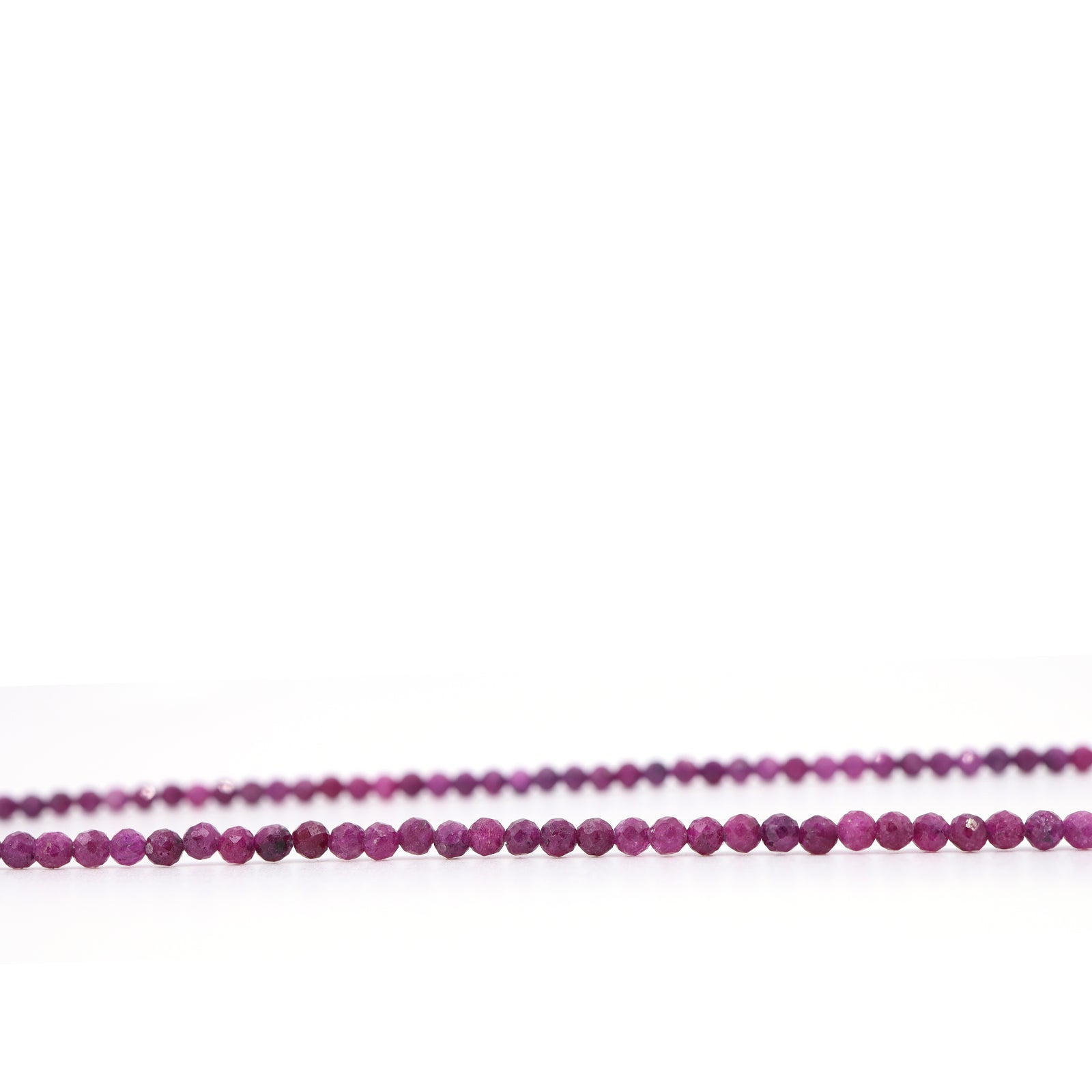 Close-up of faceted natural ruby beads showing variations in pink-red colour and texture.